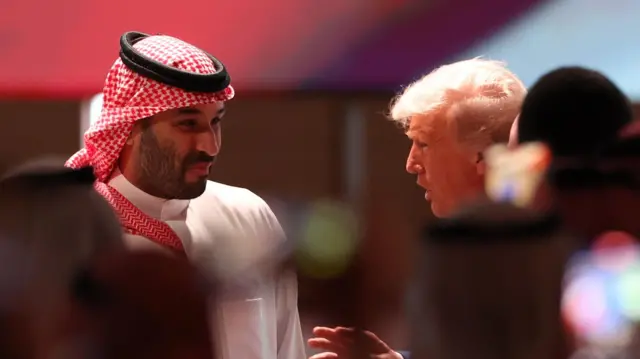 ولي العهد السعودي محمد بن سلمان والرئيس الأمريكي دونالد ترامب يتحدثان إلى بعضهما البعض. يرتدي ترامب بدلة رسمية. وولي العهد السعودي يرتدي ثوباً تقليدياً أبيض.
