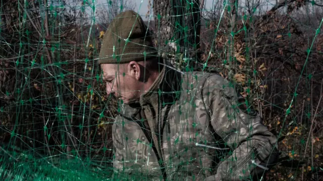 Мужчина в камуфляже за зеленой сеткой