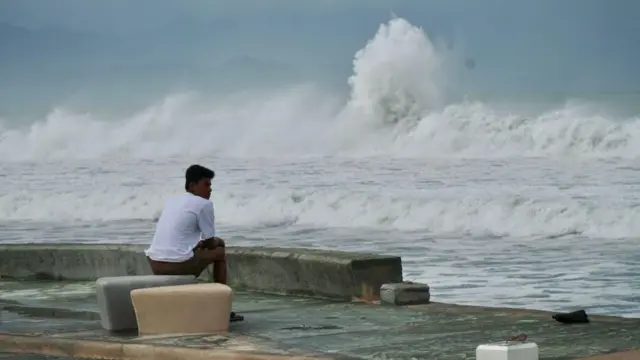সাগরের ঢেউ আছড়ে পড়ছে, সেদিকে মুখ করে বসে আছে একজন তরুণ