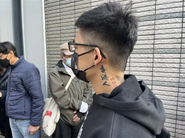 陳先生頸項上「香港人」紋身，他戴著黑口罩。