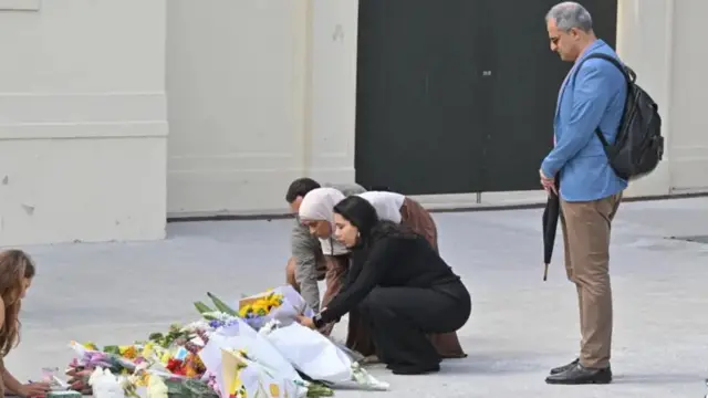 چند شهروندی در محل یادبود تیراندازی ساحل بوندای حلقه گل می‌گذارند