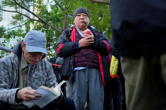 2025年12月15日，香港社運人士曾健成手持蘋果，在西九龍裁判法院外排隊等候裁決。