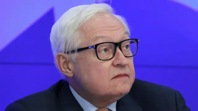 Сергей Рябков смотрит в сторону на синем фоне