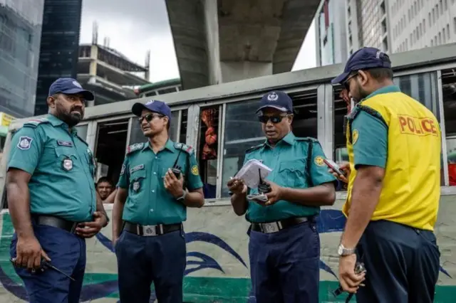 পুলিশের চার জন সদস্য ওয়াকিটকিসহ রাস্তায় দাঁড়িয়ে দায়িত্ব পালন করছেন