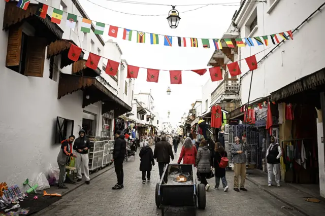 رجل ينصب أعلاماً مغربية في شارع للمشاة في الرباط، في 19 ديسمبر/كانون الأول 2025، قبل انطلاق بطولة كأس الأمم الأفريقية