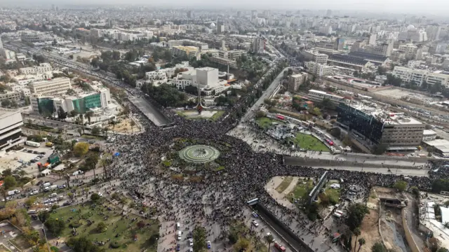 صورة التقطتها طائرة بدون طيار تُظهر أشخاصًا يتجمعون في يوم عرض عسكري، حيث يحتفل السوريون بالذكرى الأولى لسقوط بشار الأسد، في دمشق، سوريا، 8 ديسمبر/كانون الأول 2025