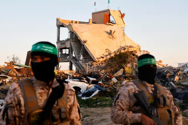يقف مسلحون من حركة حماس الفلسطينية حراساً أمام مبنى متضرر قبل إطلاق سراح الرهائن المحتجزين في خانيونس، جنوب قطاع غزة، 15 فبراير/شباط 2025