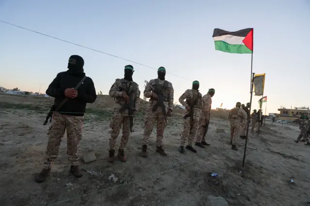 يقف مسلحون من حركة حماس الفلسطينية حراساً بينما يتجمع الناس قبل إطلاق سراح الرهائن المحتجزين، في خان يونس، جنوب قطاع غزة، 15 فبراير/شباط 2025