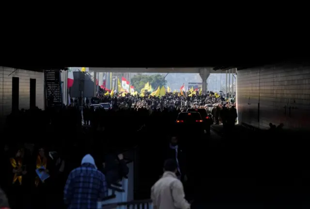 حشود تتجمع لحصور مراسم جنازة نصر الله وصفي الدين، يرفعون أعلام حزب الله والأعلام اللبنانية