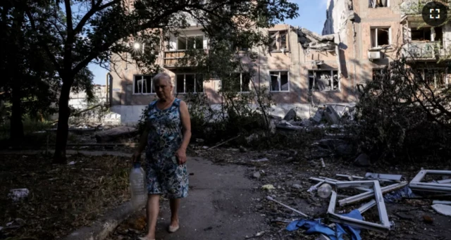 Wata mata na tafiya a garin Toretsk kusa da gidajen da yaƙi ya lalata