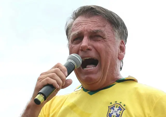 Bolsonaro falando ao microfone com camisa da seleção brasileira