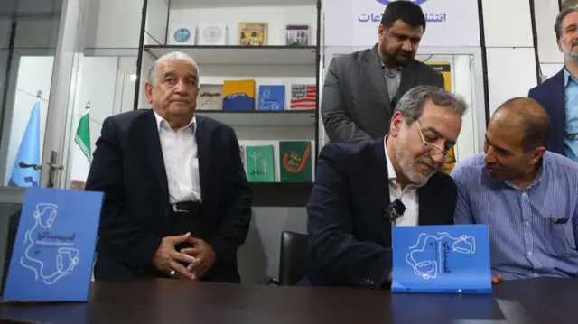 عباس عراقچی در حال امضای کتاب «قدرت مذاکره» در نمایشگاه کتاب تهران در اردیبهشت ۱۴۰۳ چند هفته پیش از شروع وزارت غیرمنتظره‌اش پس از مرگ ابراهیم رئیسی