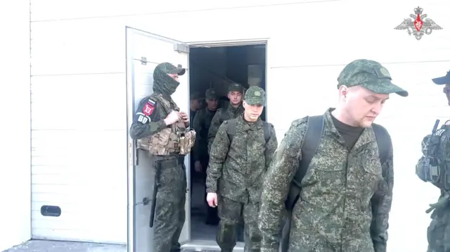 Российские военные выходят из белого здания с белой дверью