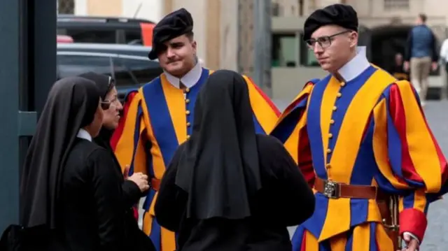 حارسان سويسريان يتحدثان إلى مجموعة من الراهبات أثناء قيامهن بدورية بالقرب من أحد مداخل الفاتيكان