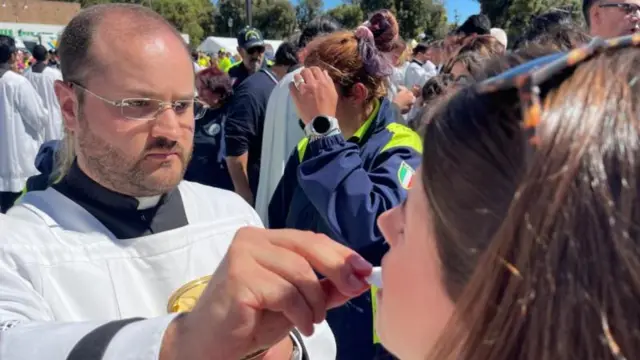 Padre dá comunhão na boca de fiel