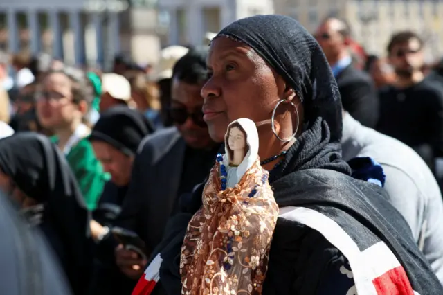 Uma mulher segura uma imagem de Nossa Senhora na Praça de São Pedro, no Vaticano