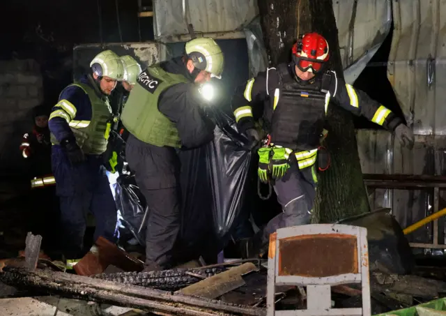 Спасатели в Харькове выносят тело одного из погибших в результате ударов