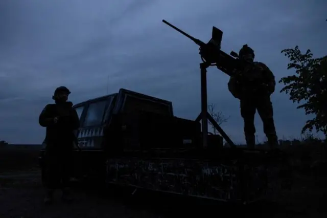 Двое украинских военных в сумерках с пулеметами