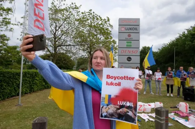 Протестующие с украинскими флагами и плакатами у Лукойла в Бельгии.