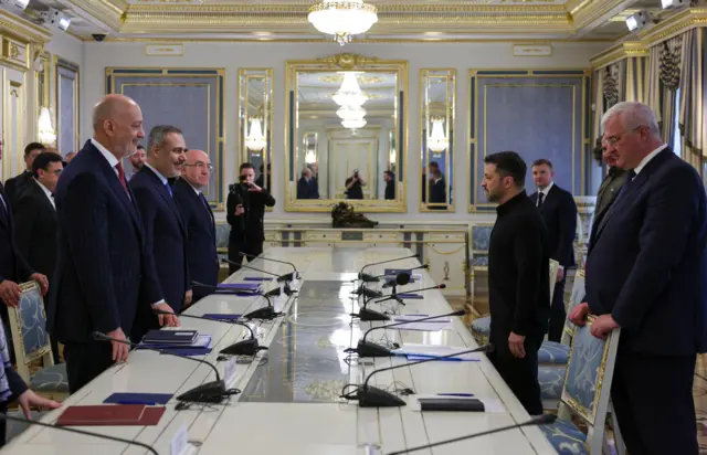 Украинские и турецкие чиновники стоят за столом переговоров перед началом встречи.