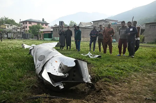 People look at a part of an aircraft in Wuyan near Indian-administered Kashmir's main city of Srinagar on May 7, 2025.