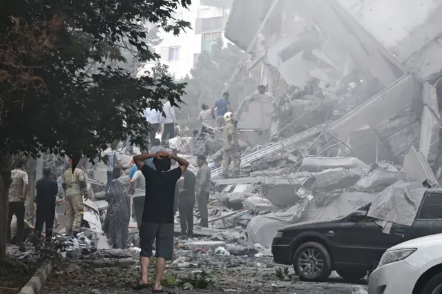 أشخاص قرب مبنى مدمر في طهران بعد ضربات إسرائيلية