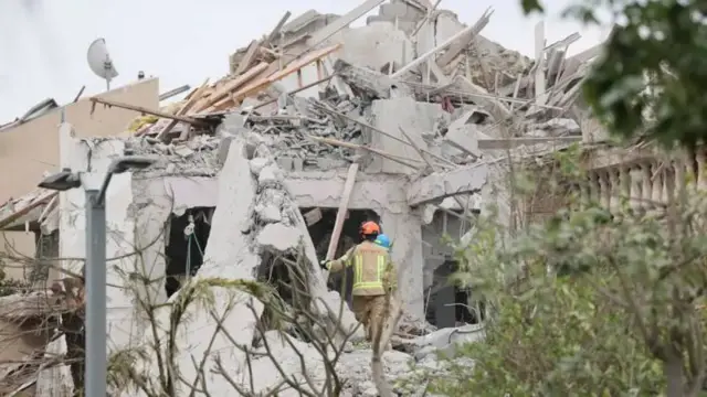 Израильские спасатели на месте попадания иранской баллистической ракеты в жилые дома