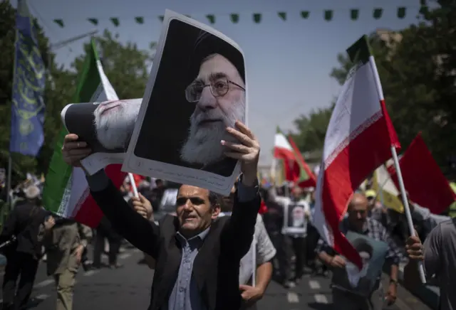 مصلٍ إيراني يرفع صور المرشد الأعلى الإيراني، آية الله علي خامنئي، خلال احتجاج لإدانة الهجمات الإسرائيلية على إيران