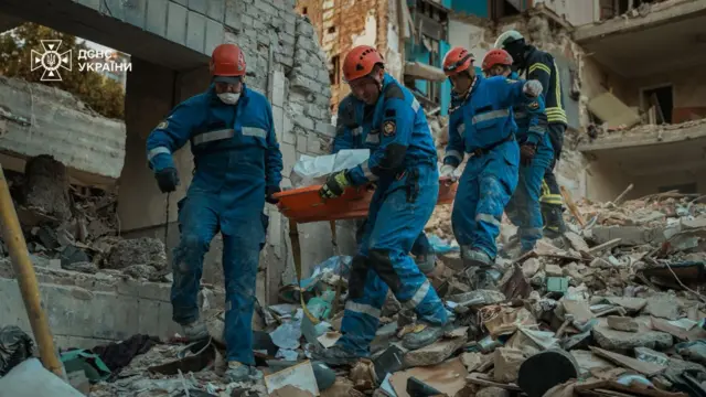 спасатели достают из завалов тело погибшего