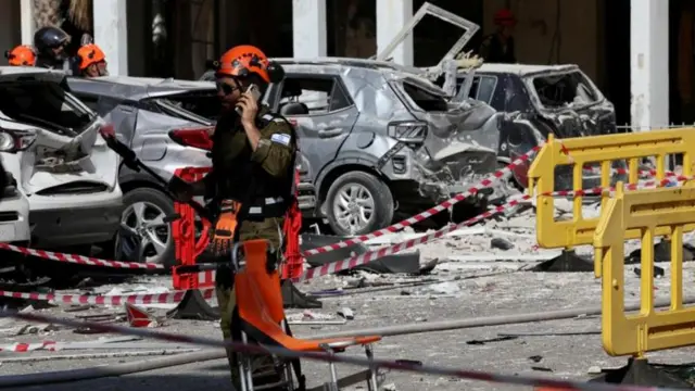 ईरानी हमले के बाद इमारत के पास फोन पर बात करता हुए एक इसराइली जवान