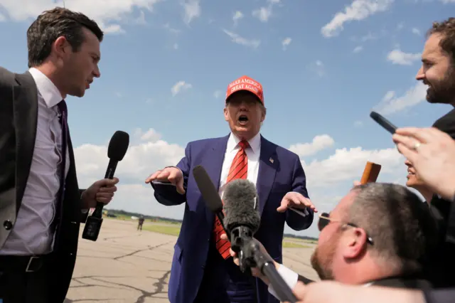 Дональд Трамп в красной кепке MAGA говорит с журналистами на летном поле