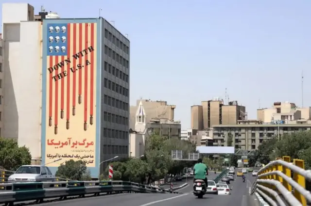 حركة مرورية بجانب مبنى عليه جدارية مناهضة للولايات المتحدة في طهران، إيران، 22 يونيو/حزيران 2025