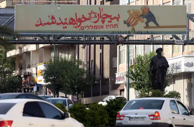 An anti-US, anti-Israel billboard reading 'You will be miserable' hangs from a pedestrian bridge in Tehran, Ira,