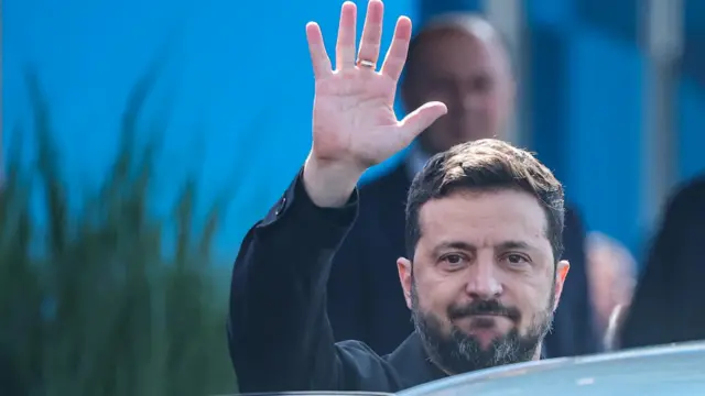 Владимир Зеленский машет рукой, садясь в машину