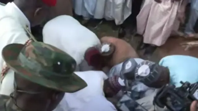 Men dressed in agbada wit cap bend down