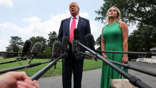 Дональд Трамп и его пресс-секретарь Кэролайн Ливитт перед микрофонами