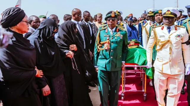 Military officials accompany di bodi of late Buhari wit oda officials by di side