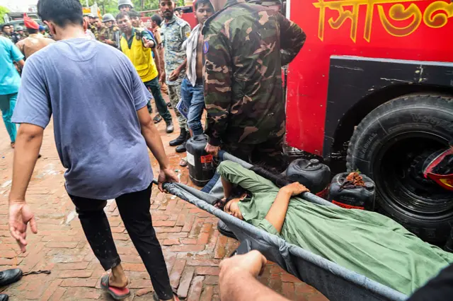 বিমান বিধ্বস্তের ঘটনায় আহত এক শিক্ষার্থীকে উদ্ধার করে হাসপাতালে নেওয়া হচ্ছে