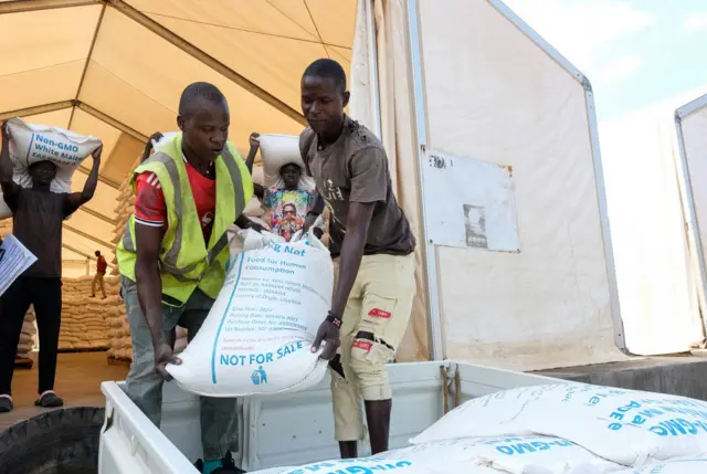 Ndị ọrụ na-ebuba ngwa nri n'ụgbọala n'ụlọ nkwakọba ihe nke ndị World Food Programme nwere