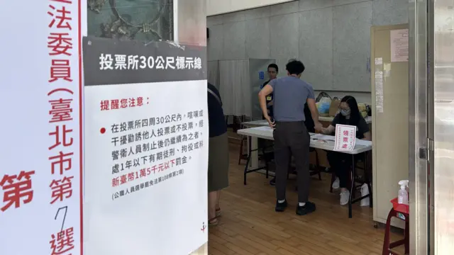 台北信義正和區民活動中心投票所內一位選民在領取「大罷免」選票（BBC中文圖片26/7/2025）