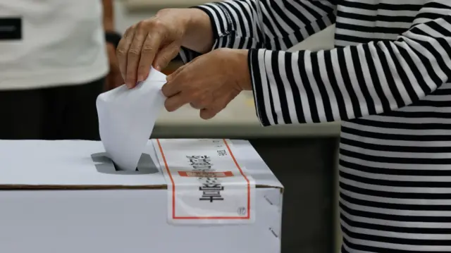 台灣「大罷免」台北大安建安國小投票站民眾將選票投入已貼上封條的投票箱（26/7/2025）