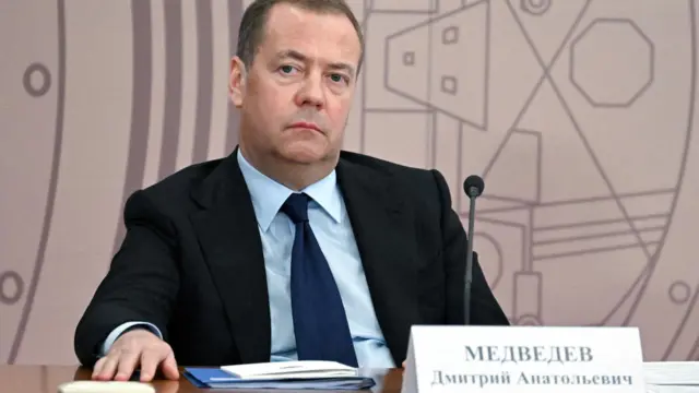 Дмитрий Медведев сидит за столом с табличкой со своей фамилией, именем и отчеством