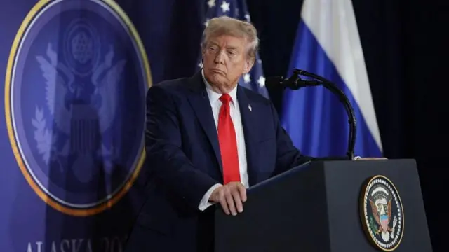 Дональд Трамп перед микрофоном задумчиво смотрит в сторону.