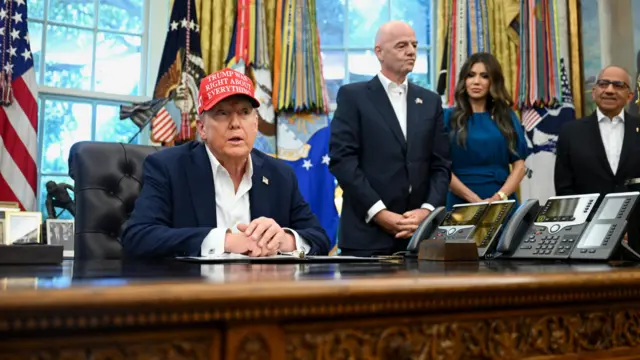 Дональд Трамп за письменным столом в красной кепке
