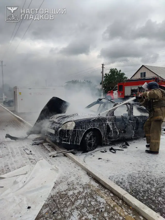 Пожарный заливает белой пеной сгоревший легковой автомобиль.