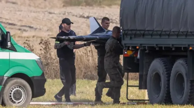 люди в форме грузят большой беспилотник в кузов грузовика