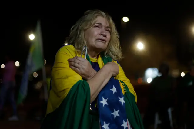 Mulher chora envolta na bandeira do Brasil