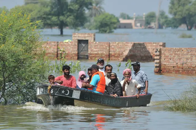 پنجاب کے شہر جلالپور پیر والا میں امدادی کارکن سیلاب میں پھنسے افراد کو کشتی کی مدد سے محفوظ مقام پر منتقل کر رہے ہیں۔
