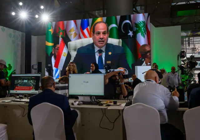 صحافيون يتابعون كلمة الرئيس المصري عبد الفتاح السيسي على شاشة في المركز الإعلامي خلال افتتاح القمة العربية الإسلامية الطارئة لمناقشة الهجوم الإسرائيلي على قطر في الدوحة، قطر، 15 سبتمبر/أيلول 2025.