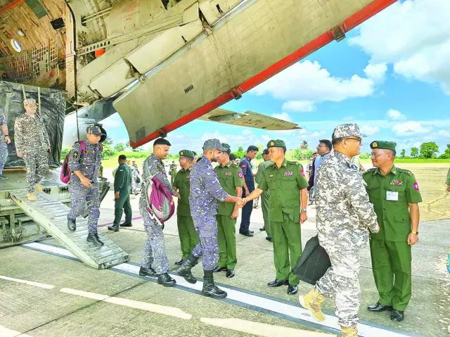 စစ်ဘက်သုံး လေယာဉ်တစ်စင်းနောက်ပိုင်းကနေ ဆင်းလာတဲ့ အိန္ဒိယ စစ်တပ် တပ်ဖွဲ့ဝင်တွေကို မြန်မာစစ်တပ် အရာရှိတစ်ချို့က လက်တွဲ နှုန်ဆက်နေတာဖြစ်ပါတယ်။ မြန်မာအရာရှိ ၄ ဦးနဲ့ အိန္ဒိယ စစ်တပ် တပ်ဖွဲ့ဝင် ၅ ဦးတို့ အပြန်အလှန် တန်းစီ လက်ဆွဲနှုတ်ဆက်နေကြတဲ့ဓာတ်ပုံ ဖြစ်ပါတယ်။